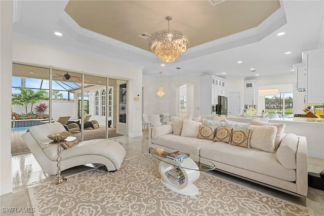 living room featuring crown molding, a chandelier, and a tray ceiling