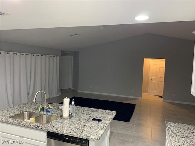 kitchen with light stone countertops, stainless steel dishwasher, sink, white cabinets, and light tile patterned flooring