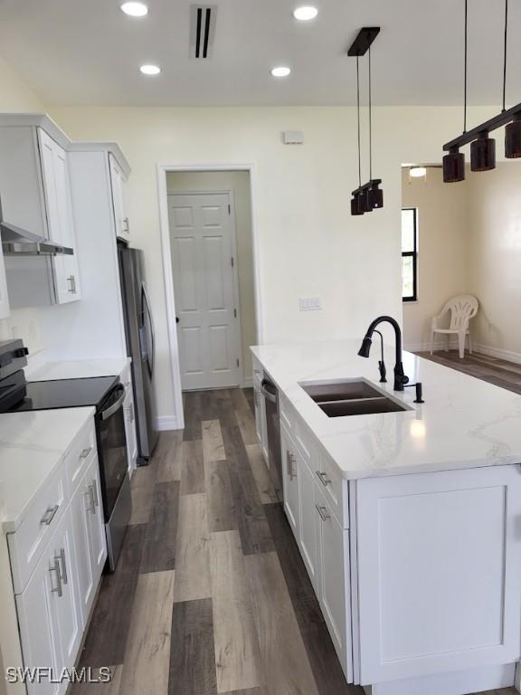 kitchen with white cabinets, sink, light stone countertops, appliances with stainless steel finishes, and decorative light fixtures