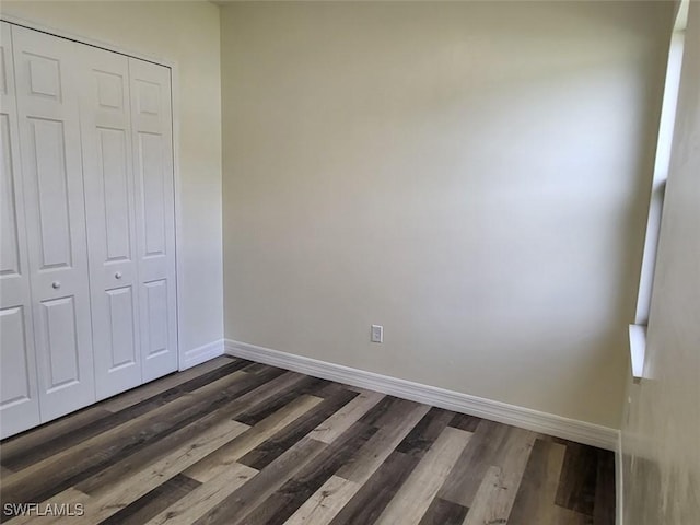 unfurnished bedroom featuring a closet and dark wood-type flooring