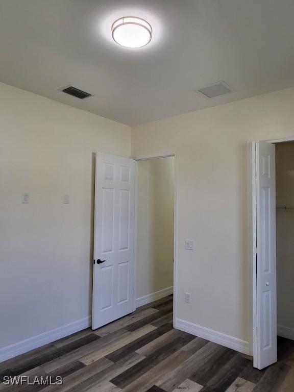 unfurnished bedroom featuring a closet and dark wood-type flooring