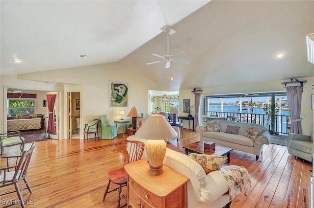 living room with light hardwood / wood-style floors, vaulted ceiling, ceiling fan, and a water view