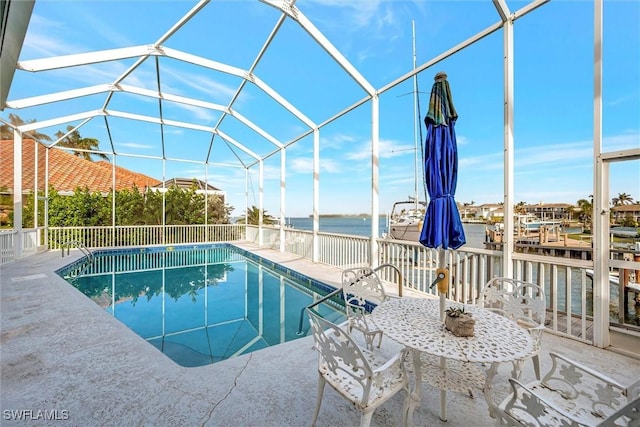 view of swimming pool with glass enclosure and a water view