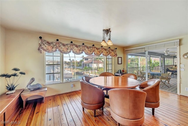 dining area with light hardwood / wood-style floors and ceiling fan with notable chandelier