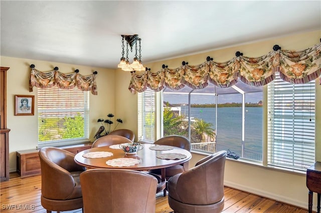 dining room with a water view and light hardwood / wood-style floors