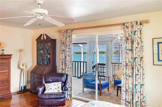 sitting room featuring a water view, ceiling fan, and wood-type flooring