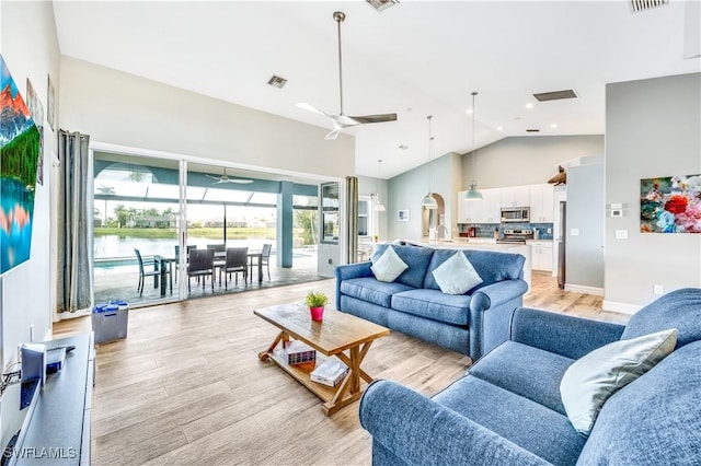 living room featuring a water view, high vaulted ceiling, ceiling fan, and light hardwood / wood-style floors