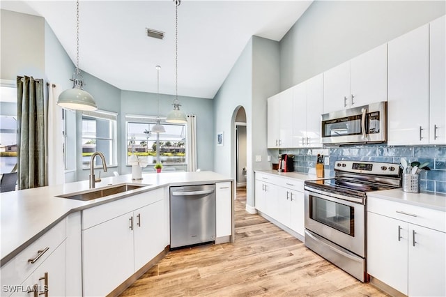 kitchen with sink, white cabinets, stainless steel appliances, and decorative light fixtures