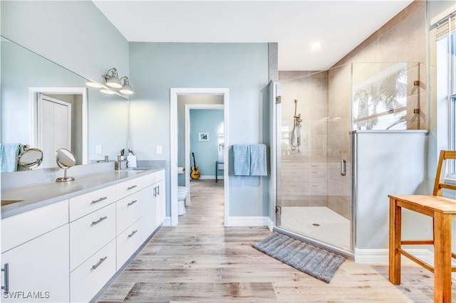 bathroom with hardwood / wood-style floors, vanity, a shower with shower door, and a wealth of natural light