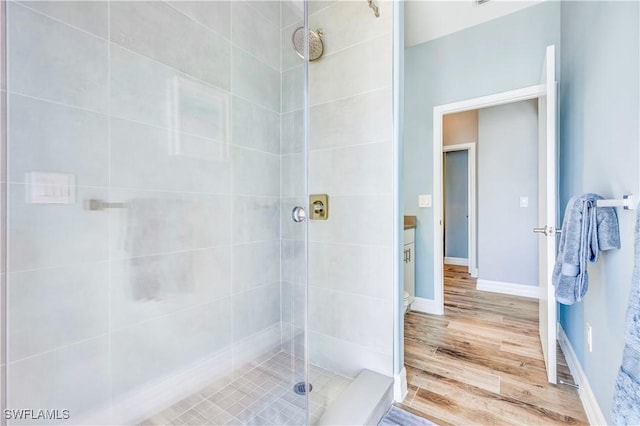 bathroom featuring a tile shower, vanity, and wood-type flooring