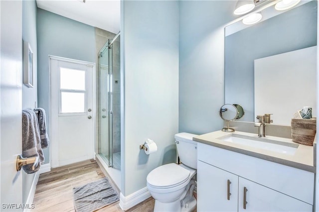 bathroom with hardwood / wood-style floors, vanity, toilet, and a shower with door