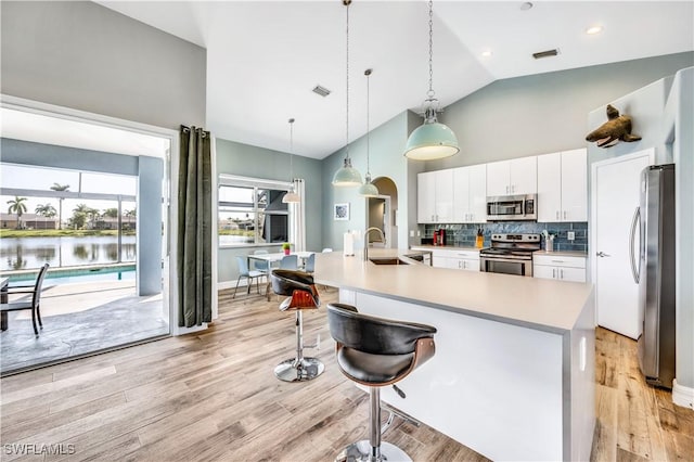 kitchen featuring backsplash, sink, hanging light fixtures, appliances with stainless steel finishes, and white cabinetry