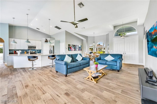 living room featuring ceiling fan, light wood-type flooring, and high vaulted ceiling