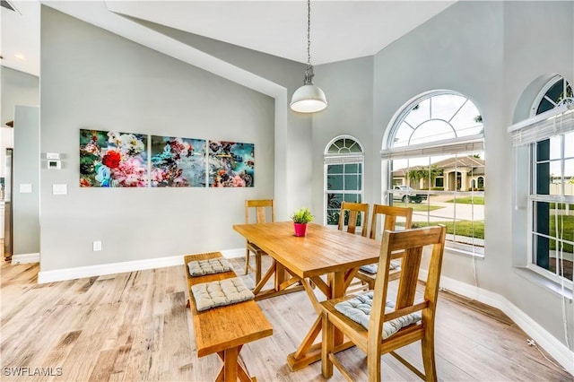 dining area featuring high vaulted ceiling and light wood-type flooring