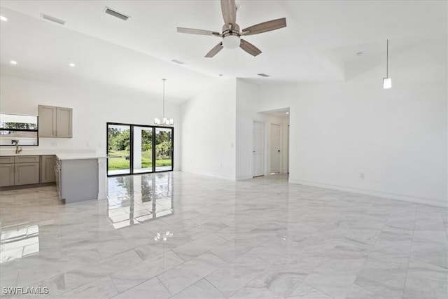 unfurnished living room with vaulted ceiling, sink, and ceiling fan with notable chandelier