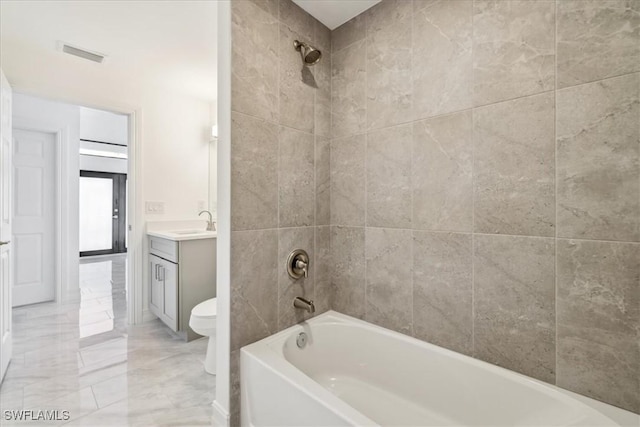 full bathroom featuring tiled shower / bath combo, toilet, and vanity