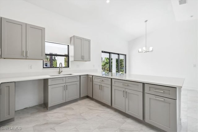 kitchen with kitchen peninsula, sink, gray cabinetry, and hanging light fixtures