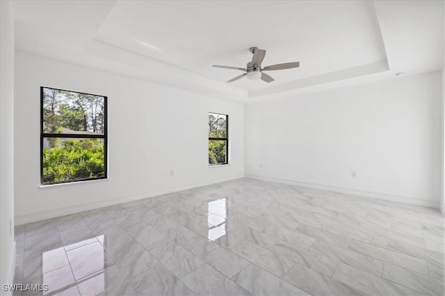 spare room with ceiling fan and a raised ceiling