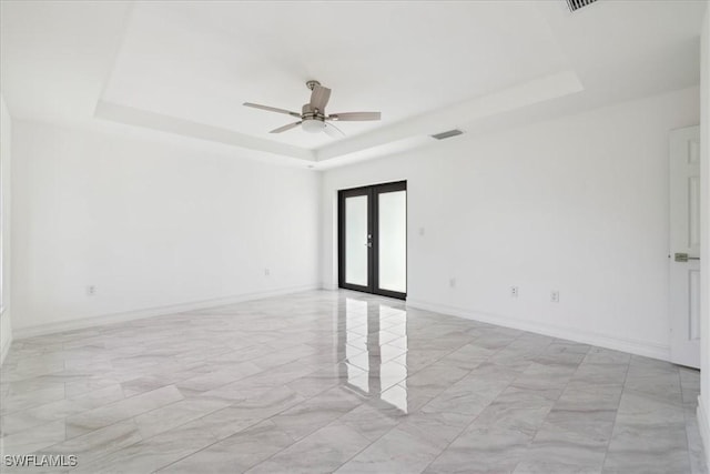 spare room with ceiling fan, french doors, and a tray ceiling