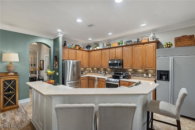 kitchen featuring a spacious island, ornamental molding, stainless steel appliances, and a breakfast bar area