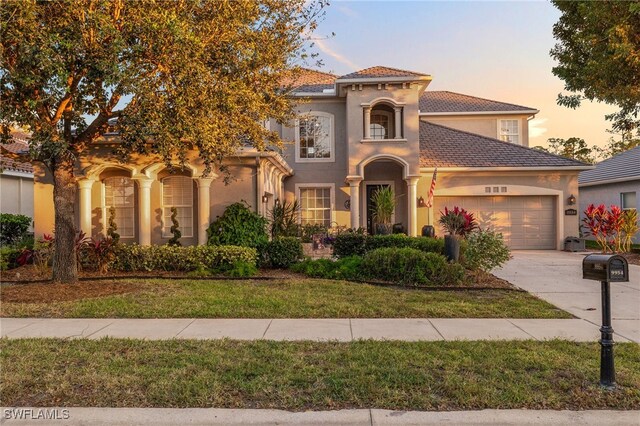 9954 Via Loop, San Marco Loop, Fort Myers, FL 33905 - mediterranean / spanish-style home featuring an attached garage, driveway, stucco siding, and a yard