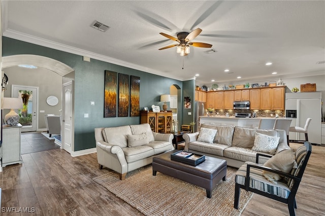 living room with hardwood / wood-style flooring, ceiling fan, and crown molding