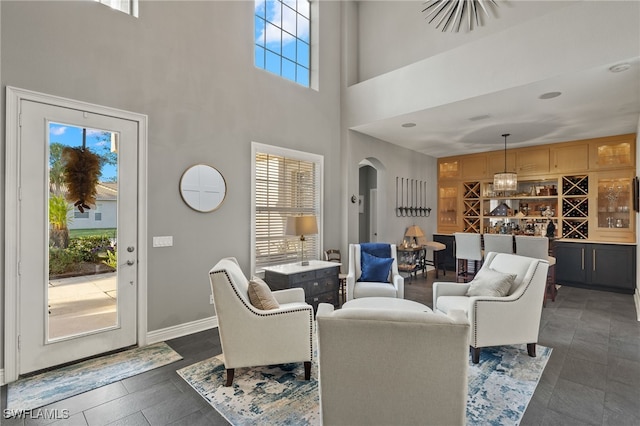 living room featuring plenty of natural light, a high ceiling, and bar area