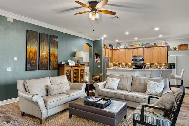 living room with ceiling fan, crown molding, and light hardwood / wood-style flooring