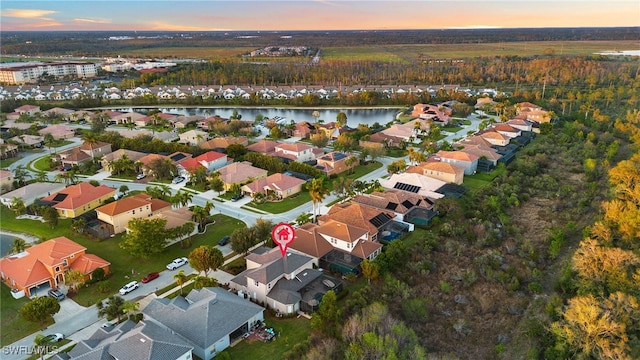 aerial view at dusk featuring a water view