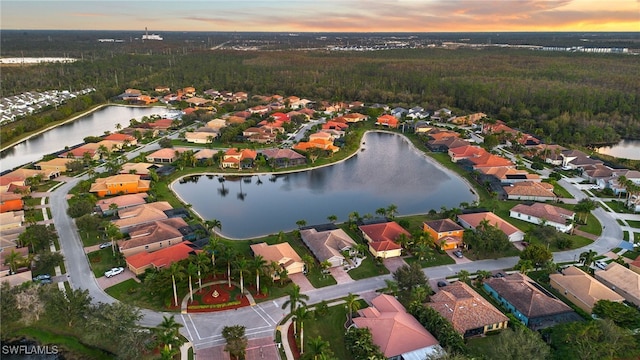 aerial view at dusk featuring a water view