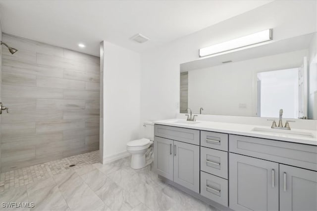 bathroom featuring a tile shower, vanity, and toilet