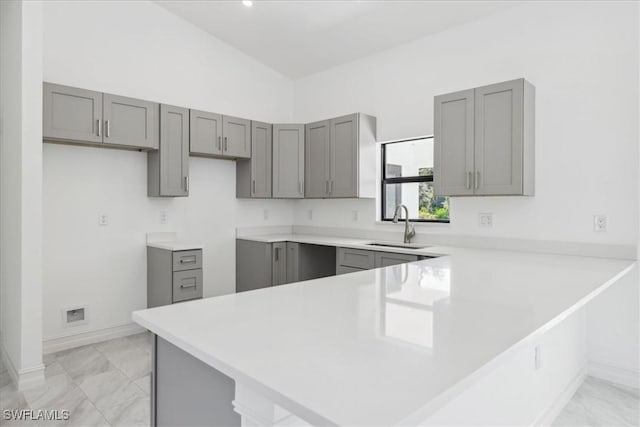 kitchen featuring kitchen peninsula, gray cabinets, and sink