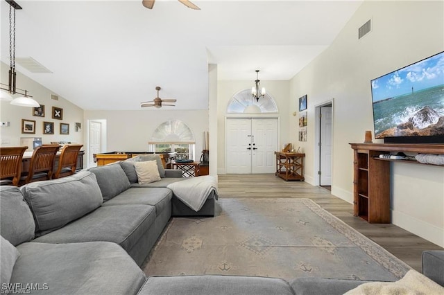 living room featuring vaulted ceiling, hardwood / wood-style floors, ceiling fan with notable chandelier, and pool table