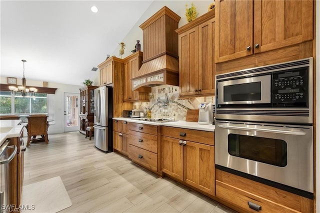 kitchen with pendant lighting, lofted ceiling, decorative backsplash, appliances with stainless steel finishes, and a chandelier