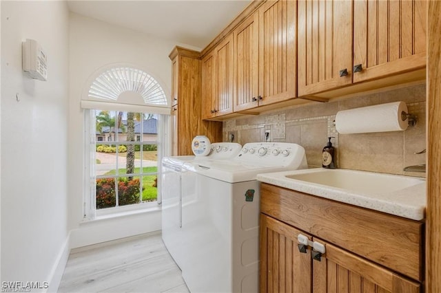 laundry room with washer and clothes dryer, plenty of natural light, light hardwood / wood-style floors, and cabinets