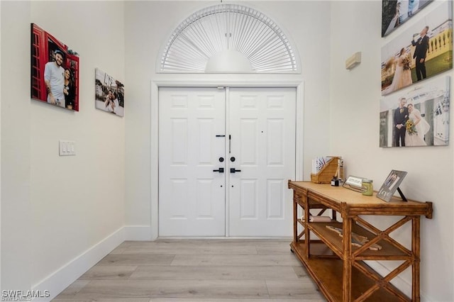 foyer entrance with light hardwood / wood-style flooring and a high ceiling