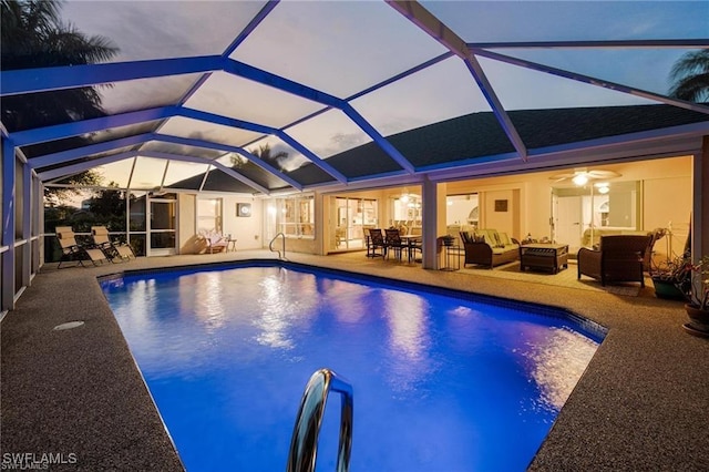 pool at dusk with outdoor lounge area, ceiling fan, a patio, and glass enclosure