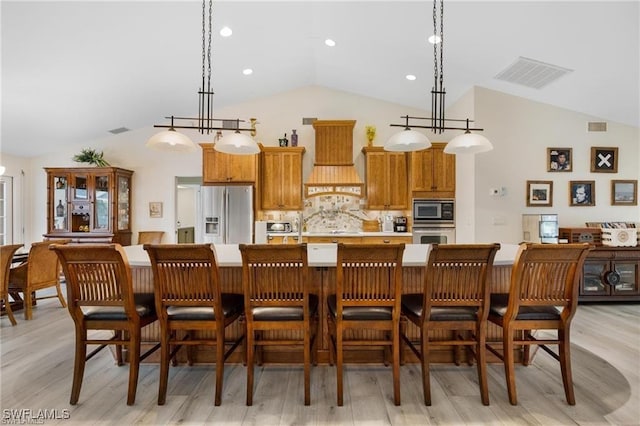 kitchen featuring tasteful backsplash, decorative light fixtures, vaulted ceiling, and appliances with stainless steel finishes