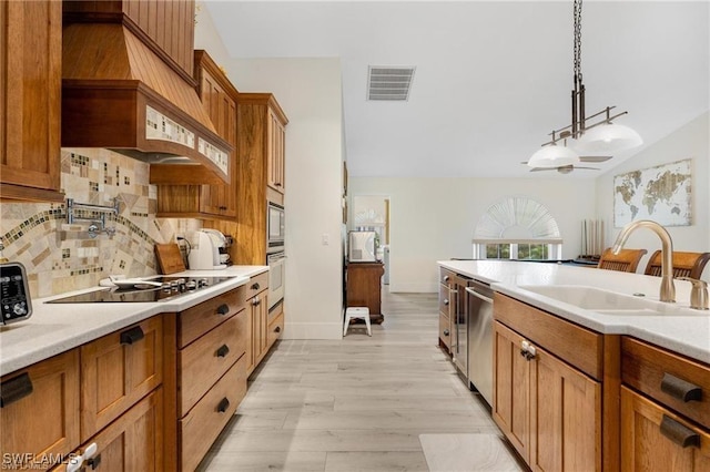 kitchen with tasteful backsplash, custom range hood, stainless steel appliances, sink, and hanging light fixtures