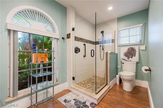 bathroom featuring a wealth of natural light, toilet, walk in shower, and hardwood / wood-style floors