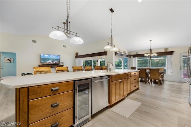 kitchen featuring lofted ceiling, sink, hanging light fixtures, stainless steel dishwasher, and beverage cooler