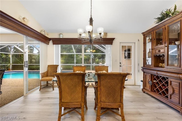 dining space featuring a chandelier, vaulted ceiling, and light wood-type flooring