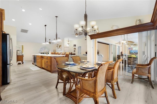 dining room with light hardwood / wood-style flooring, vaulted ceiling, and a notable chandelier