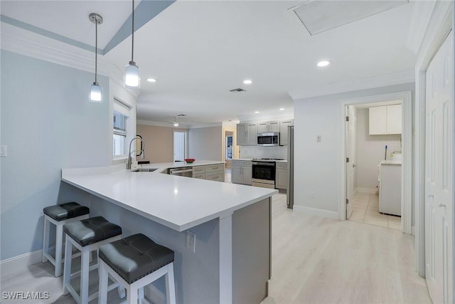 kitchen featuring sink, a kitchen breakfast bar, kitchen peninsula, decorative light fixtures, and appliances with stainless steel finishes