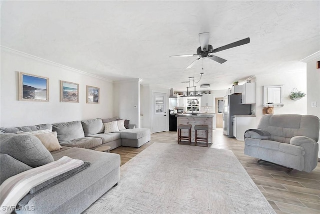 living room with ceiling fan, ornamental molding, and light wood-type flooring