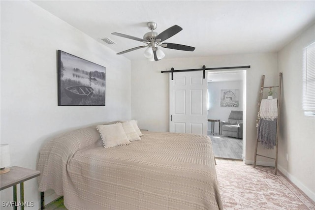 bedroom featuring ceiling fan and a barn door