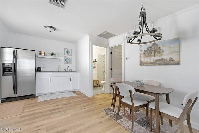 dining area with crown molding, an inviting chandelier, and light wood-type flooring