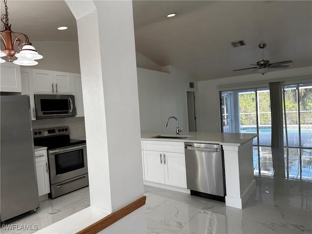 kitchen featuring ceiling fan with notable chandelier, stainless steel appliances, sink, white cabinets, and hanging light fixtures