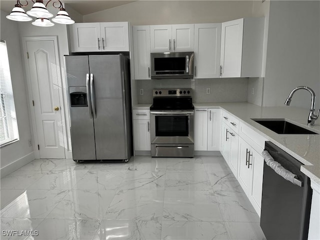 kitchen featuring light stone countertops, appliances with stainless steel finishes, sink, decorative light fixtures, and white cabinets