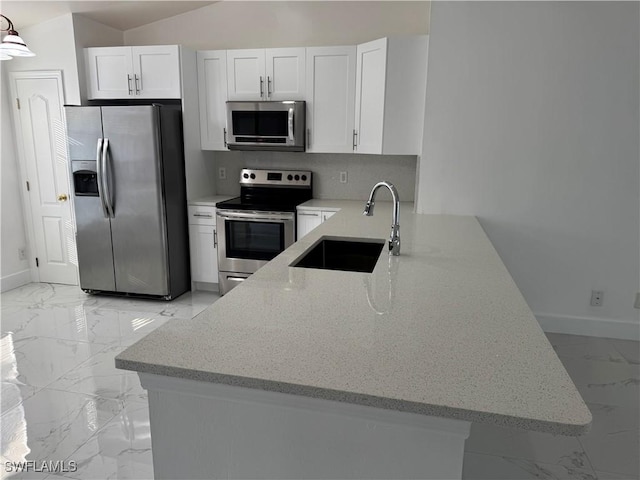 kitchen featuring white cabinets, sink, appliances with stainless steel finishes, light stone counters, and kitchen peninsula